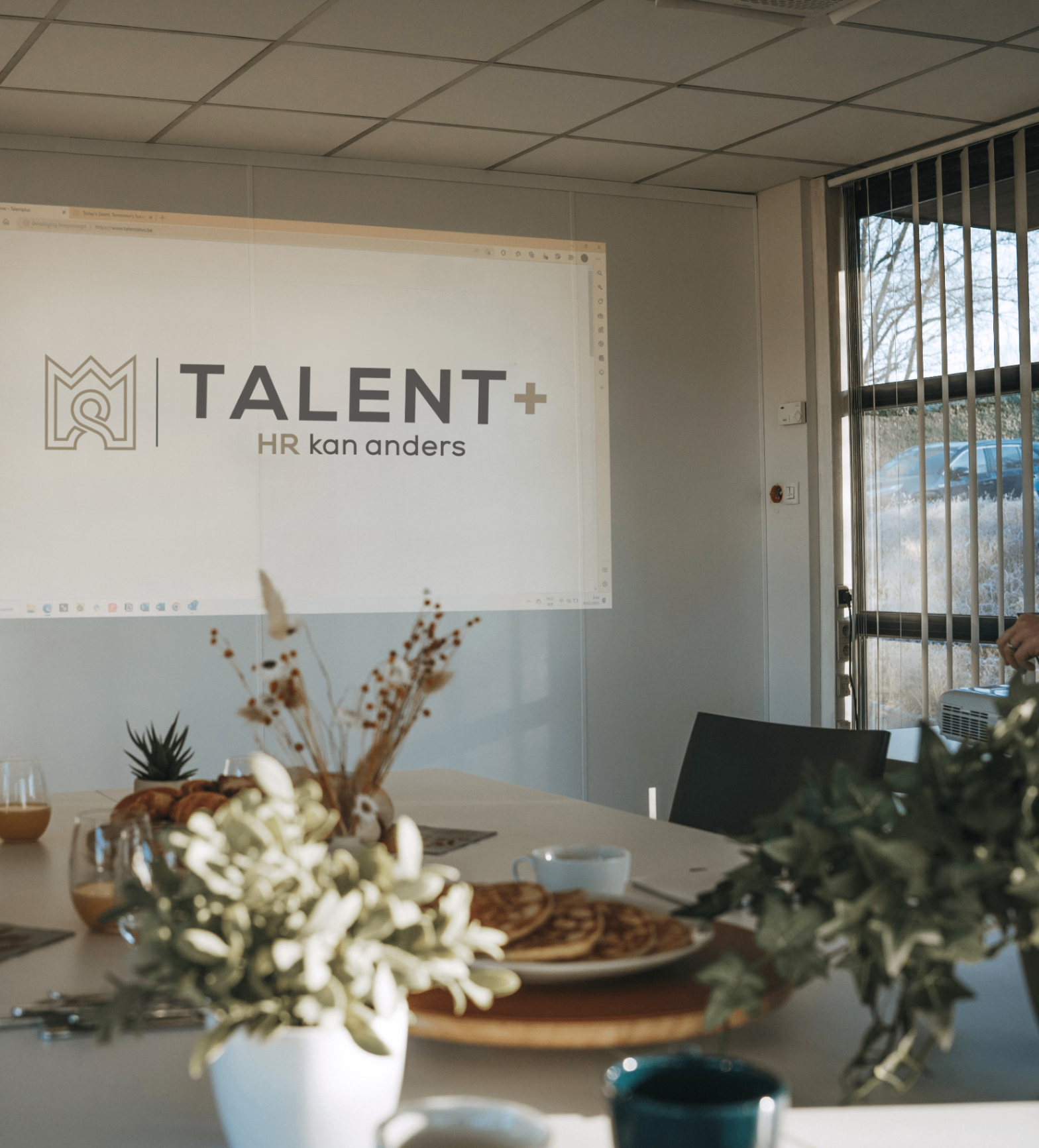 Sfeerbeeld van het Talent+ kantoor in Ternat met logo geprojecteerd tijdens een meeting